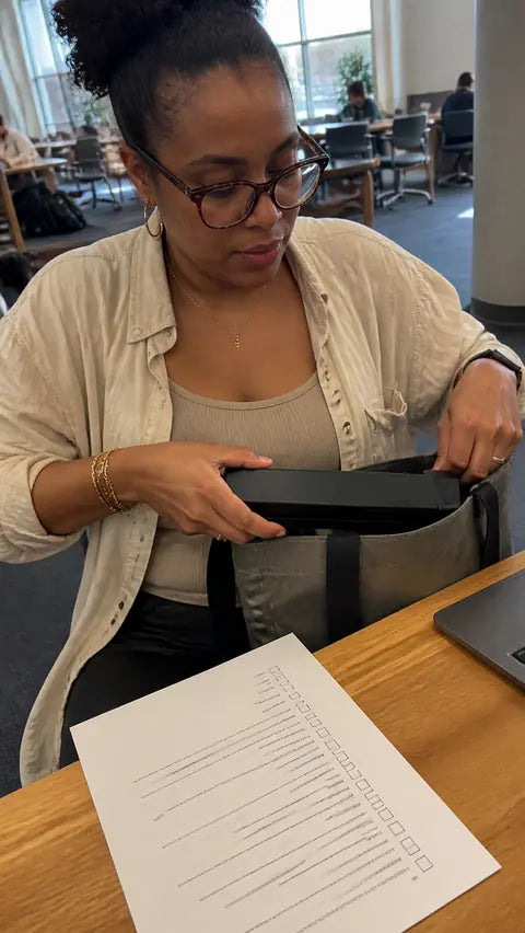 Freelancer packing the black PAUD portable printer into a work bag