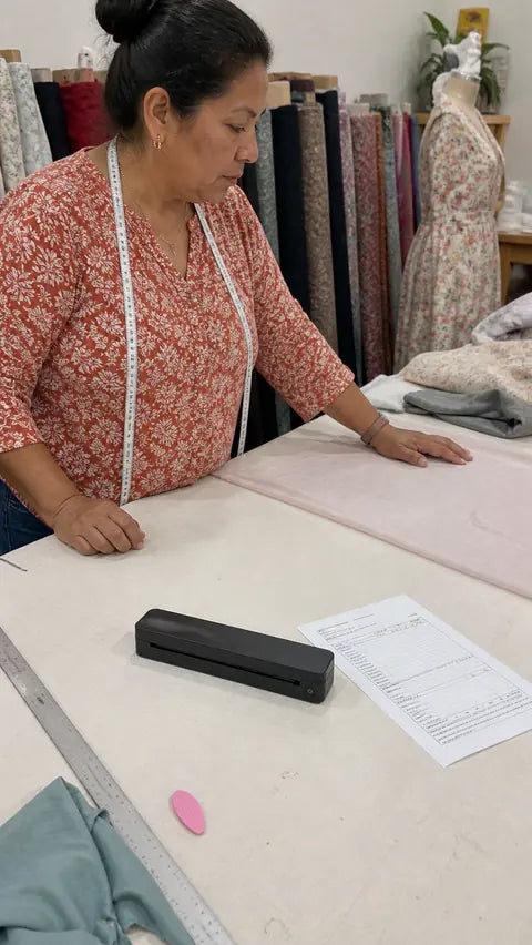 Sewing studio owner using the black PAUD portable printer for order forms